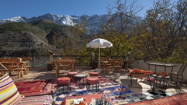 Un patio al aire libre con asientos, una mesa y vistas a montañas nevadas.