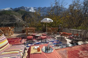 An outdoor patio with seating, a table, and a view of snow-capped mountains. - Dar Adrar (Asni)