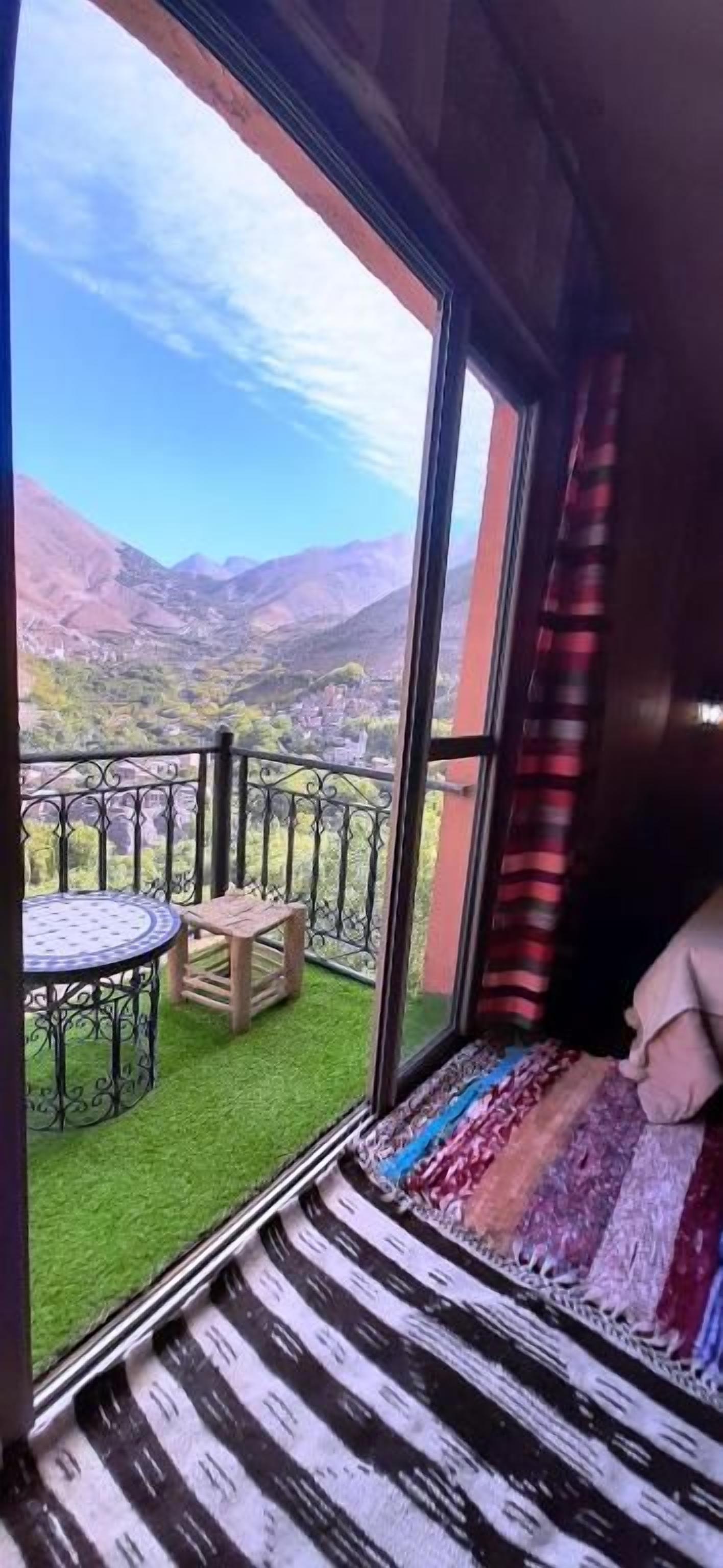 Un balcón con vistas a montañas, una mesita redonda y una banca.