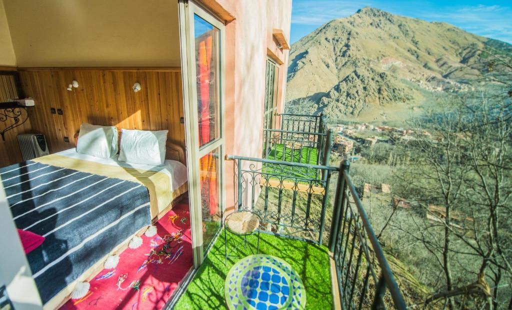 Un dormitorio con cama, ventana y balcón con vistas a la montaña.