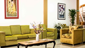 A green sofa, a yellow armchair, a coffee table, and two framed artworks on the wall. - Hotel Prado 72 (Barranquilla)