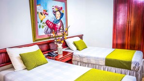 A hotel room with two beds, each with a white and green bedspread, a nightstand with a phone, and a vase with flowers. - Hotel Prado 72 (Barranquilla)