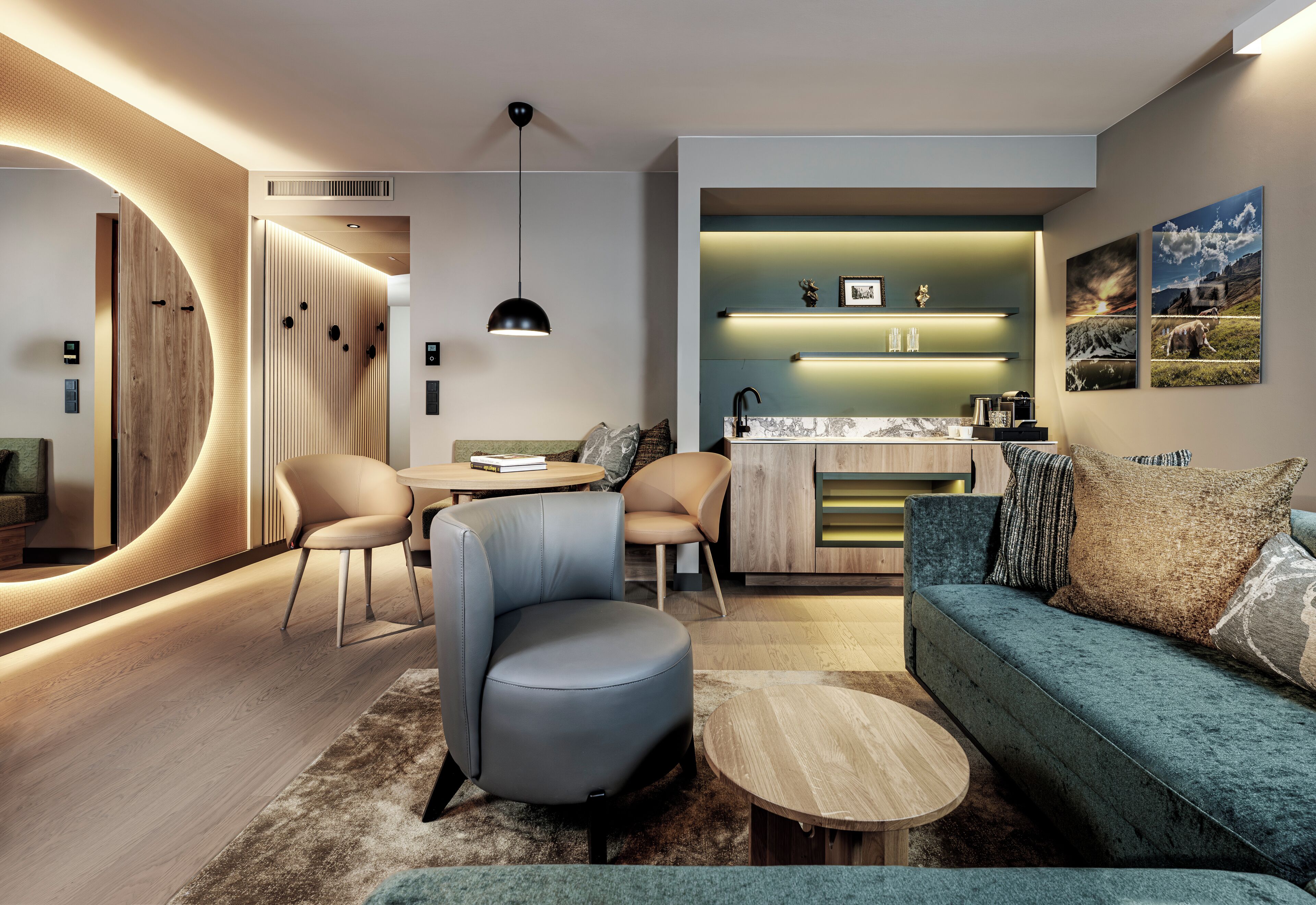 A modern living room with a sofa, chairs, a coffee table, and a kitchen area with a countertop and shelves.
