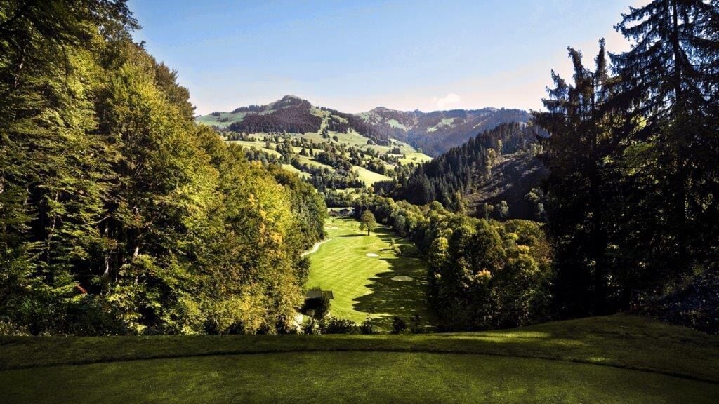 A golf course with a view of rolling hills and dense forests.
