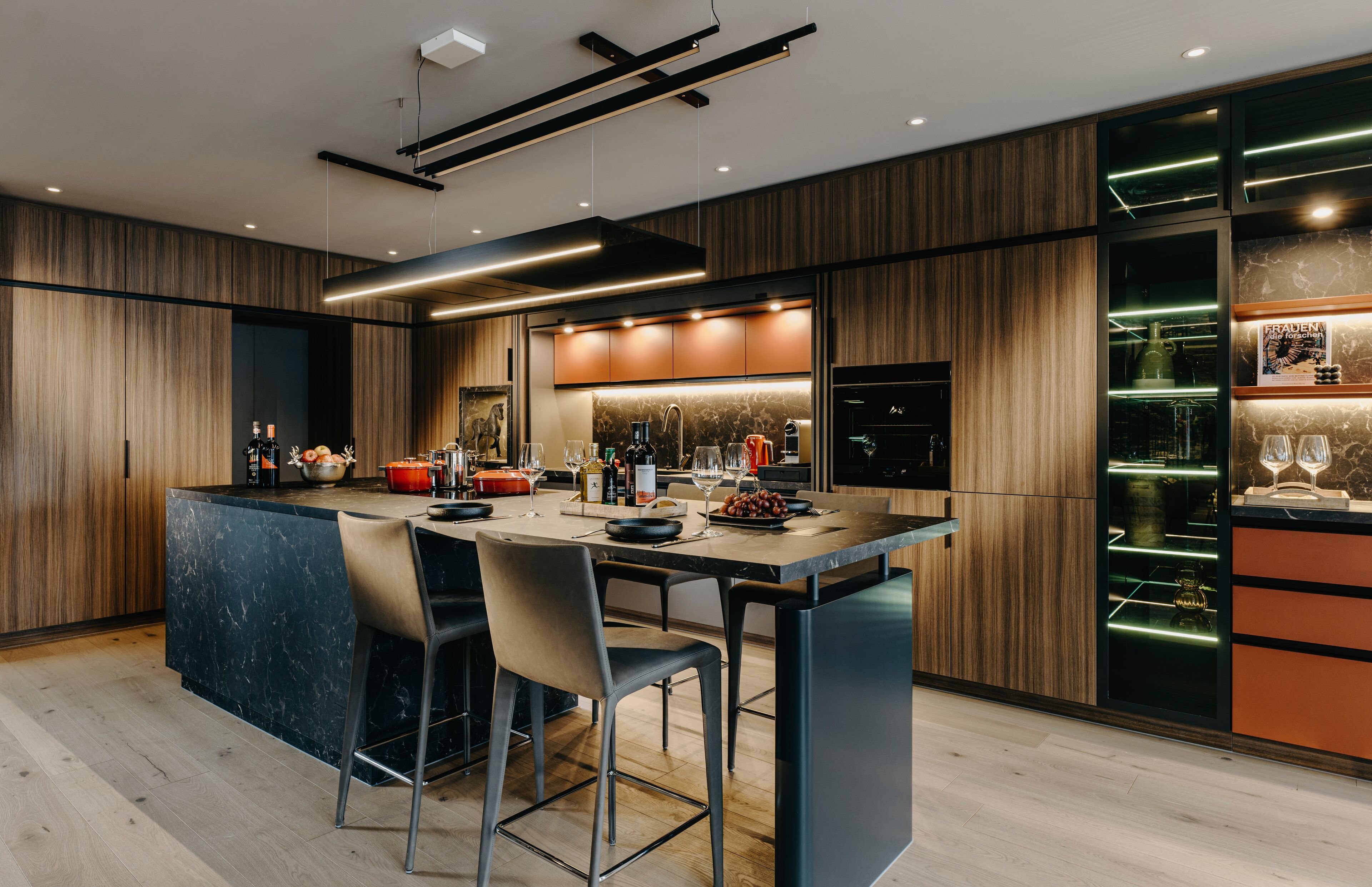 Una cocina moderna con una isla central, taburetes de bar y electrodomésticos integrados.