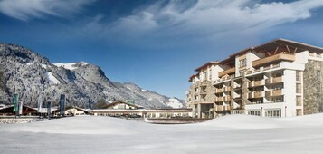 Un hotel con varios balcones, un paisaje montañoso y un terreno cubierto de nieve.