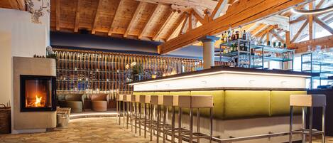 A bar area with a stone floor, wooden ceiling beams, and a fireplace.