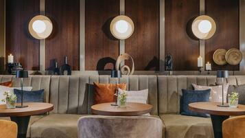 Un área de lounge moderna con un sofá, mesas redondas y lámparas fijadas a la pared.
