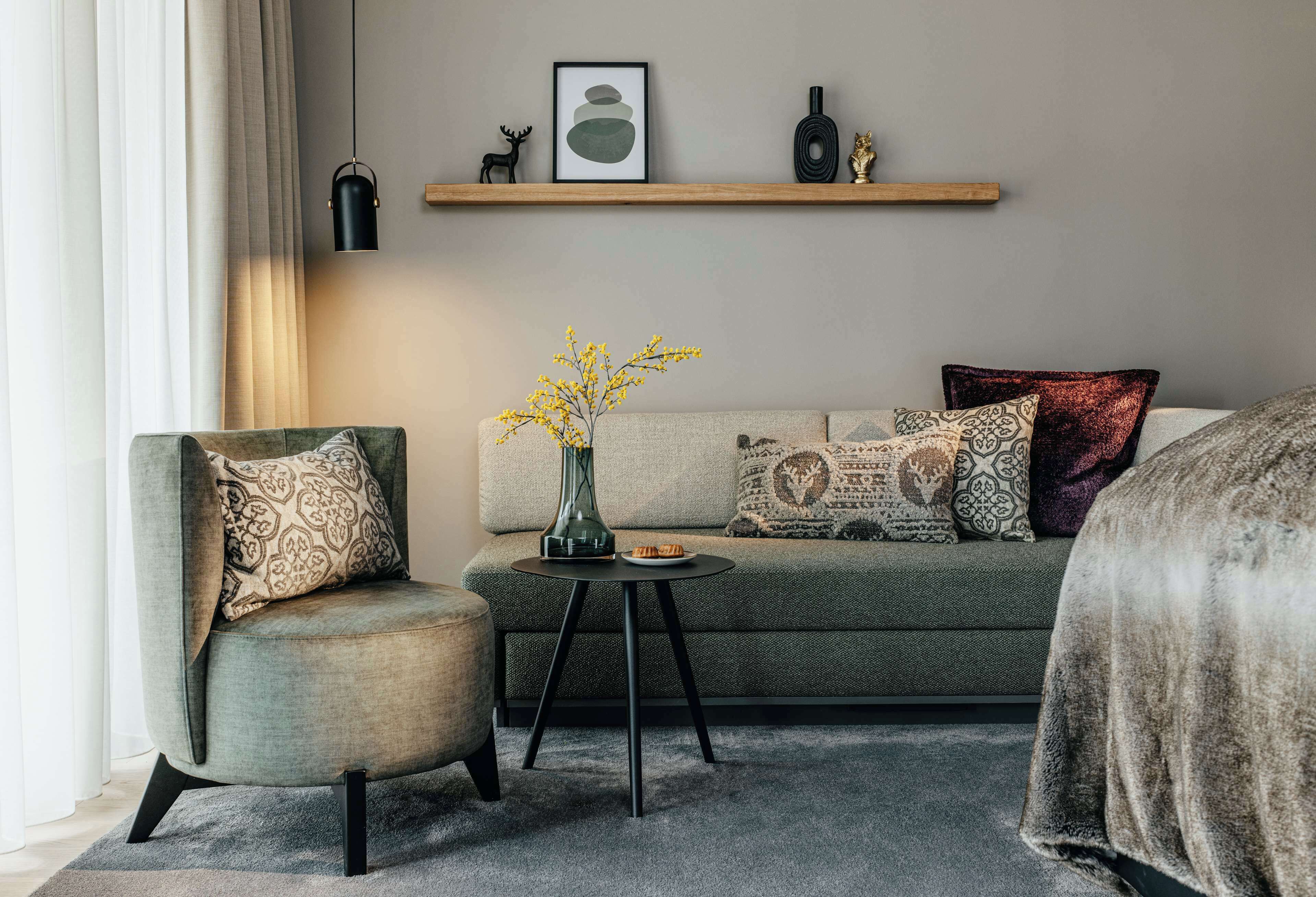 A modern living room with a sofa, armchair, and a small table with a vase and plate.