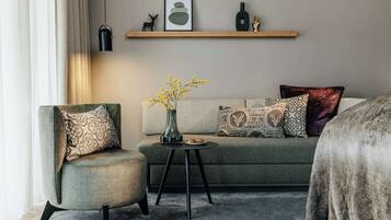 A modern living room with a sofa, armchair, and a small table with a vase and plate.