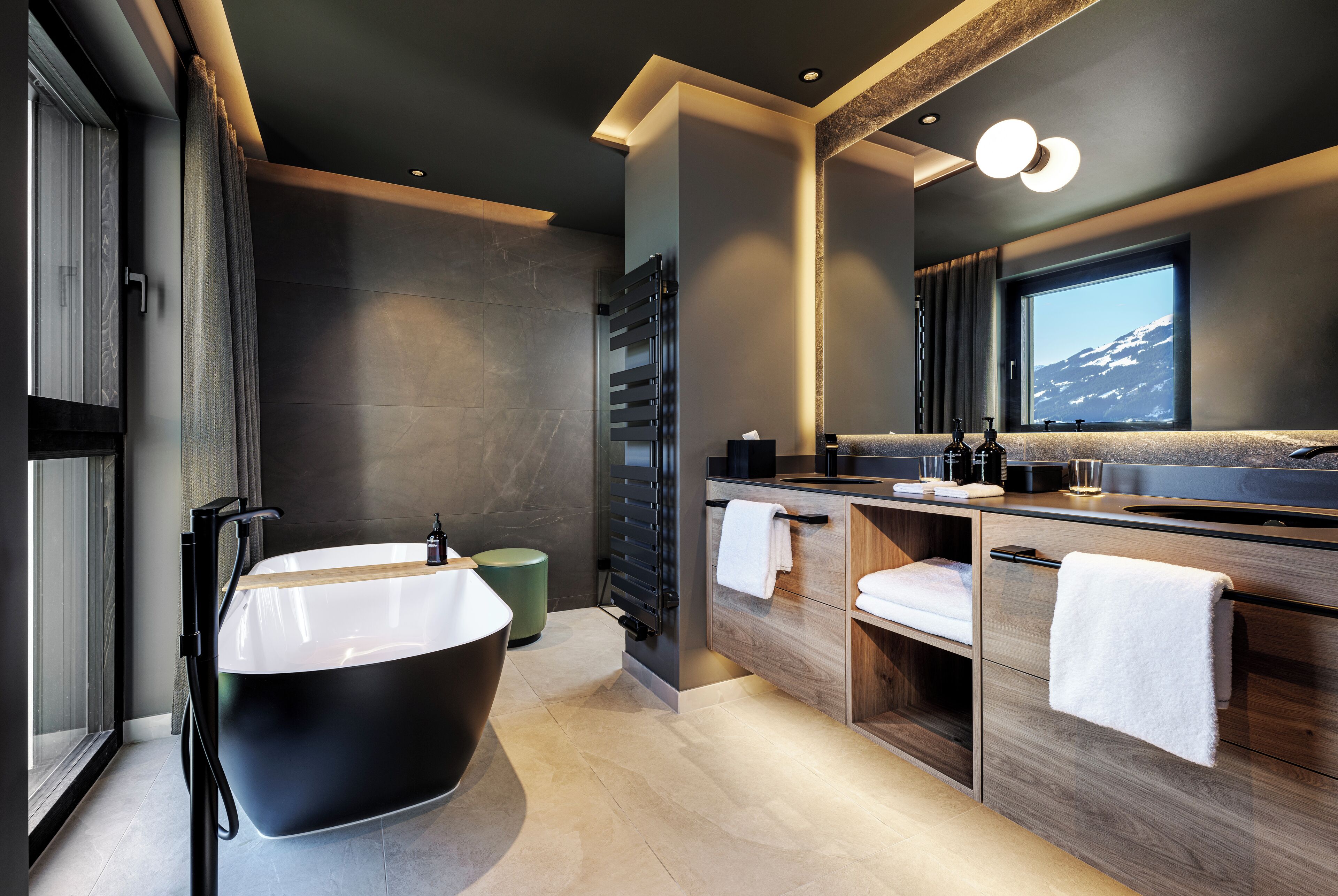 A modern bathroom with a freestanding bathtub, wooden vanity, and a large mirror.