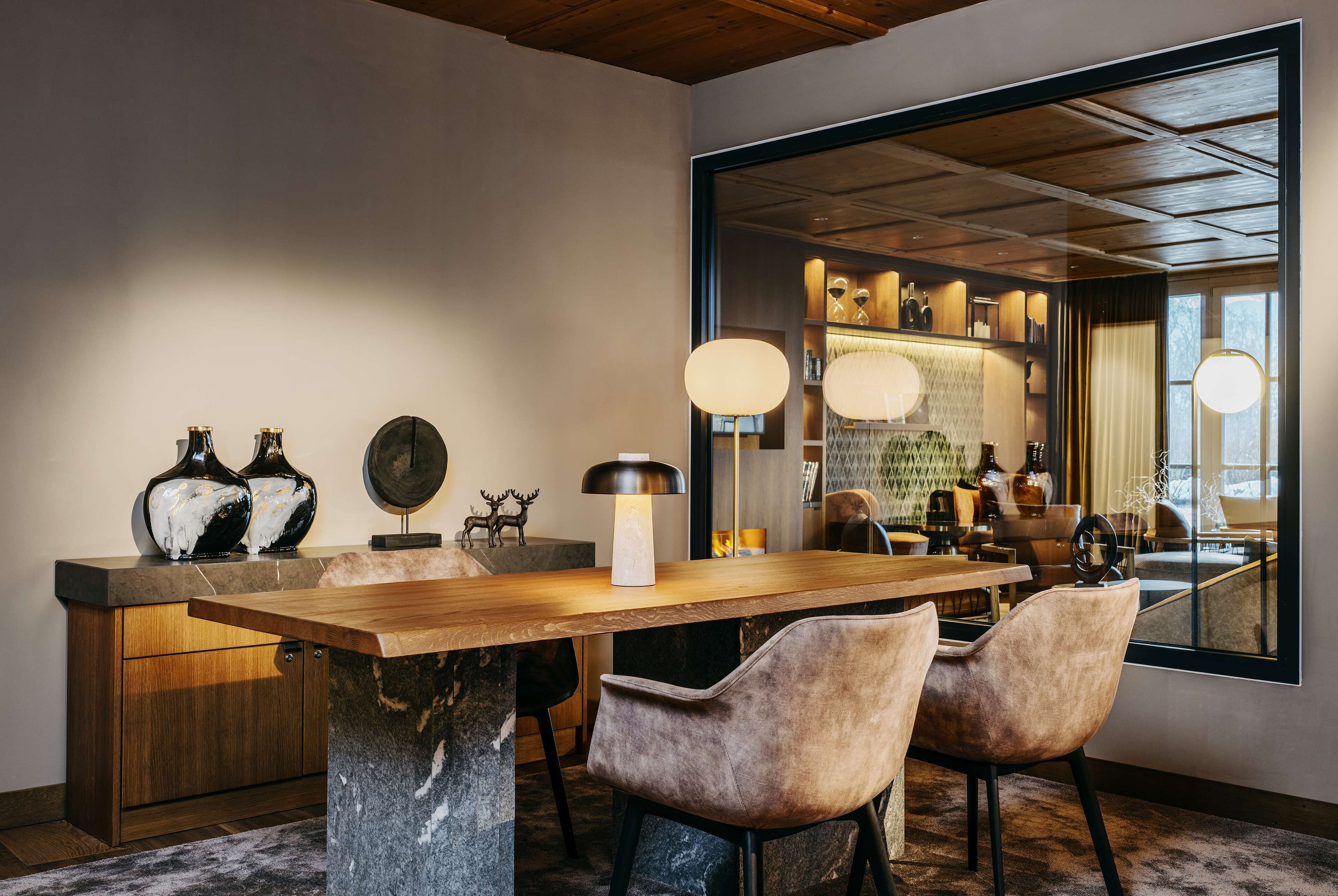 Un espace repas moderne avec une table en bois, deux fauteuils confortables et un piédestal en marbre.