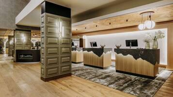 A modern reception area with a wooden reception desk, a large pillar, and a patterned rug.