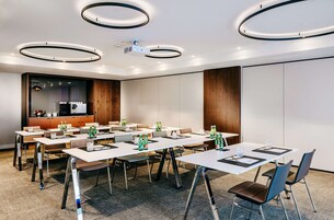 Un salón de conferencias con varias mesas, sillas y un proyector.