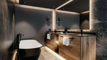 A modern bathroom with a freestanding bathtub, wooden vanity, and a large mirror.