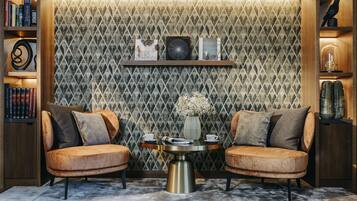 A cozy seating area with two cushioned chairs, a small round table, and a bookshelf.