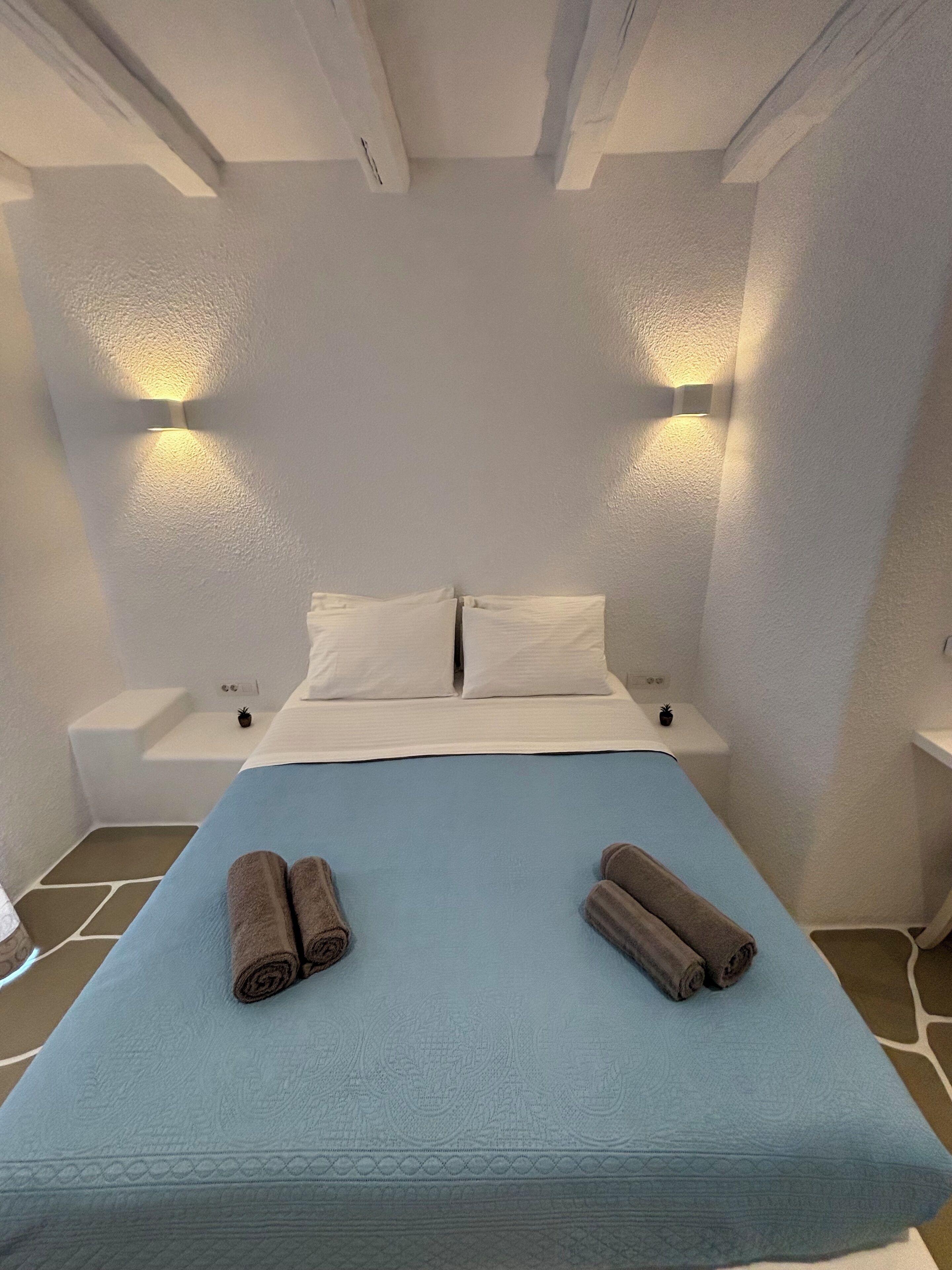 A bedroom with a bed, two nightstands, and two wall-mounted lights.