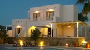 A modern two-story building with a pool, outdoor seating, and a covered patio area. - Olga's Pension (Ios)