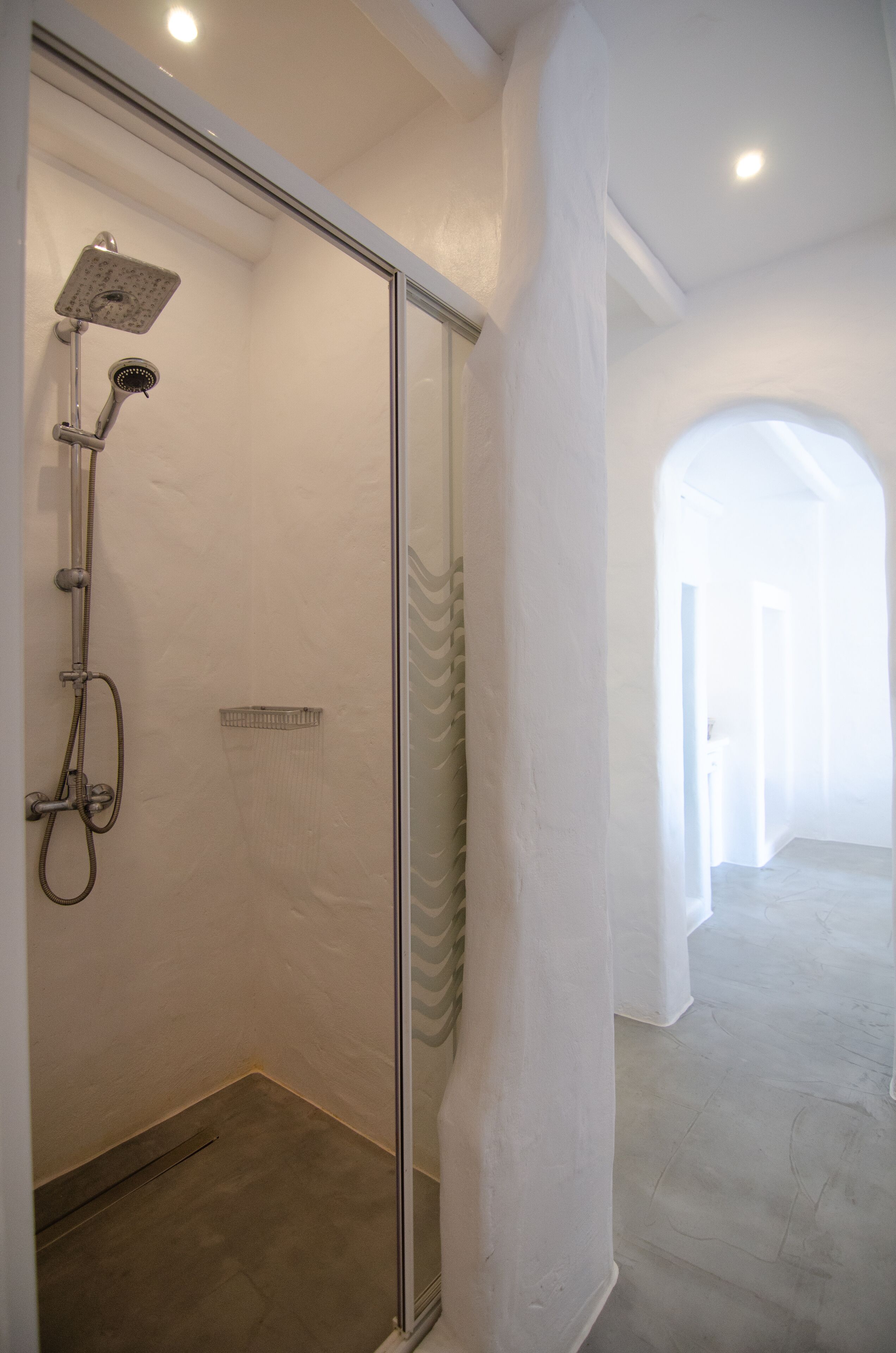 A modern bathroom with a glass shower enclosure, a handheld showerhead, and a wall-mounted faucet.