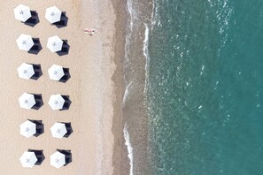 En la playa, sillas reclinables de playa, sombrillas, toallas de playa
