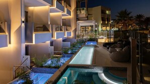 A modern hotel with a pool area, outdoor seating, and a restaurant visible in the background. -  Pearl SeaBreeze Suites (Rethymno)