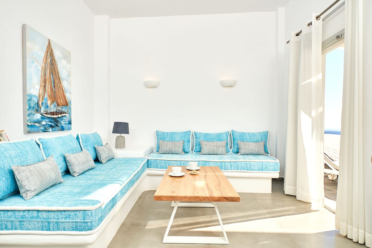 Uma sala de estar moderna com um sofá modular, uma mesa de centro de madeira e um quadro de um veleiro.