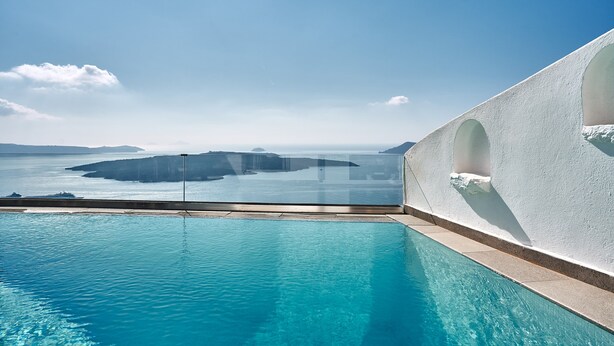 Cielo azul despejado, una piscina y vistas al mar con islas a lo lejos.