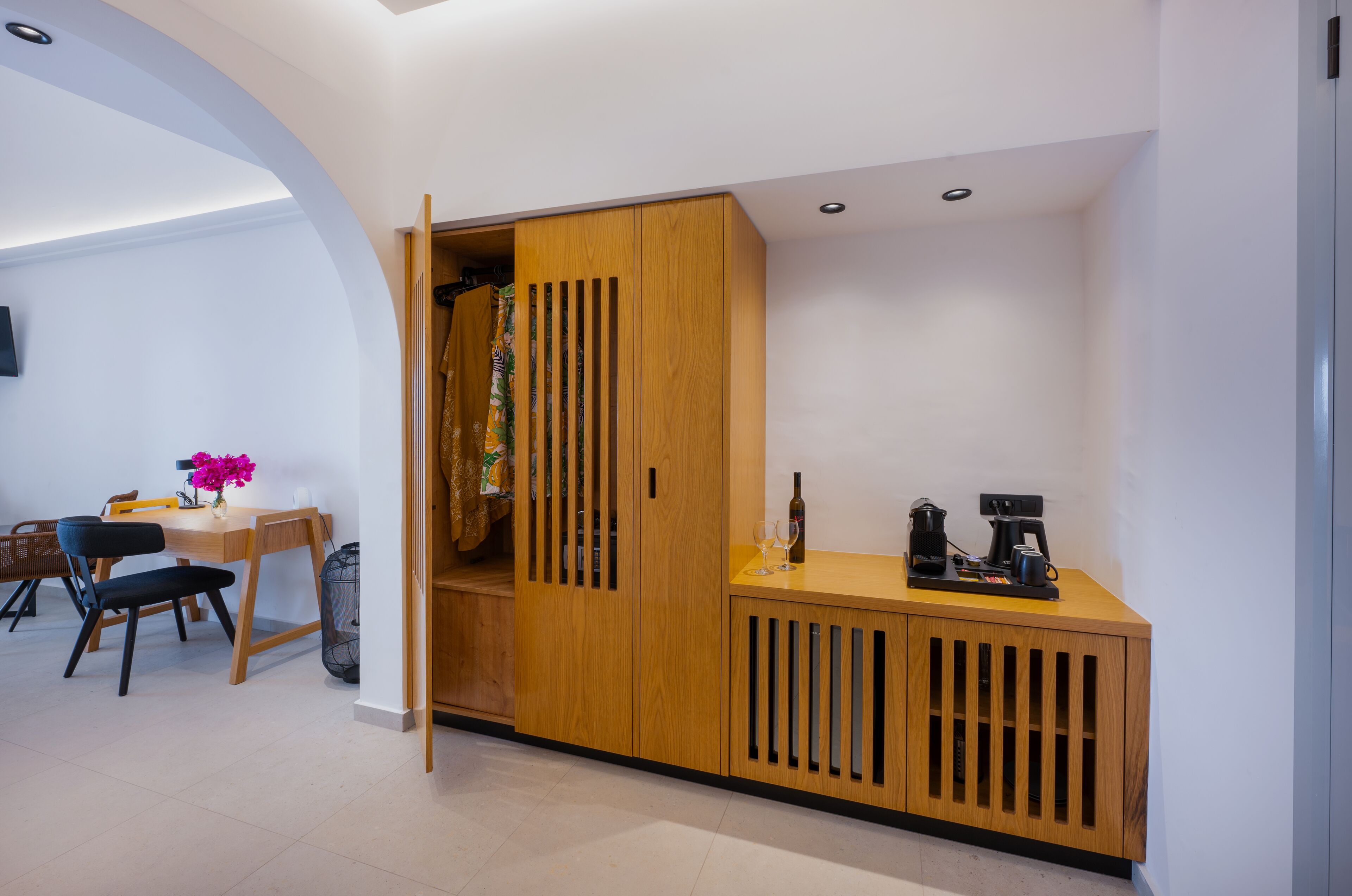 A modern room with a wooden wardrobe, a small table with a vase, and a coffee machine.