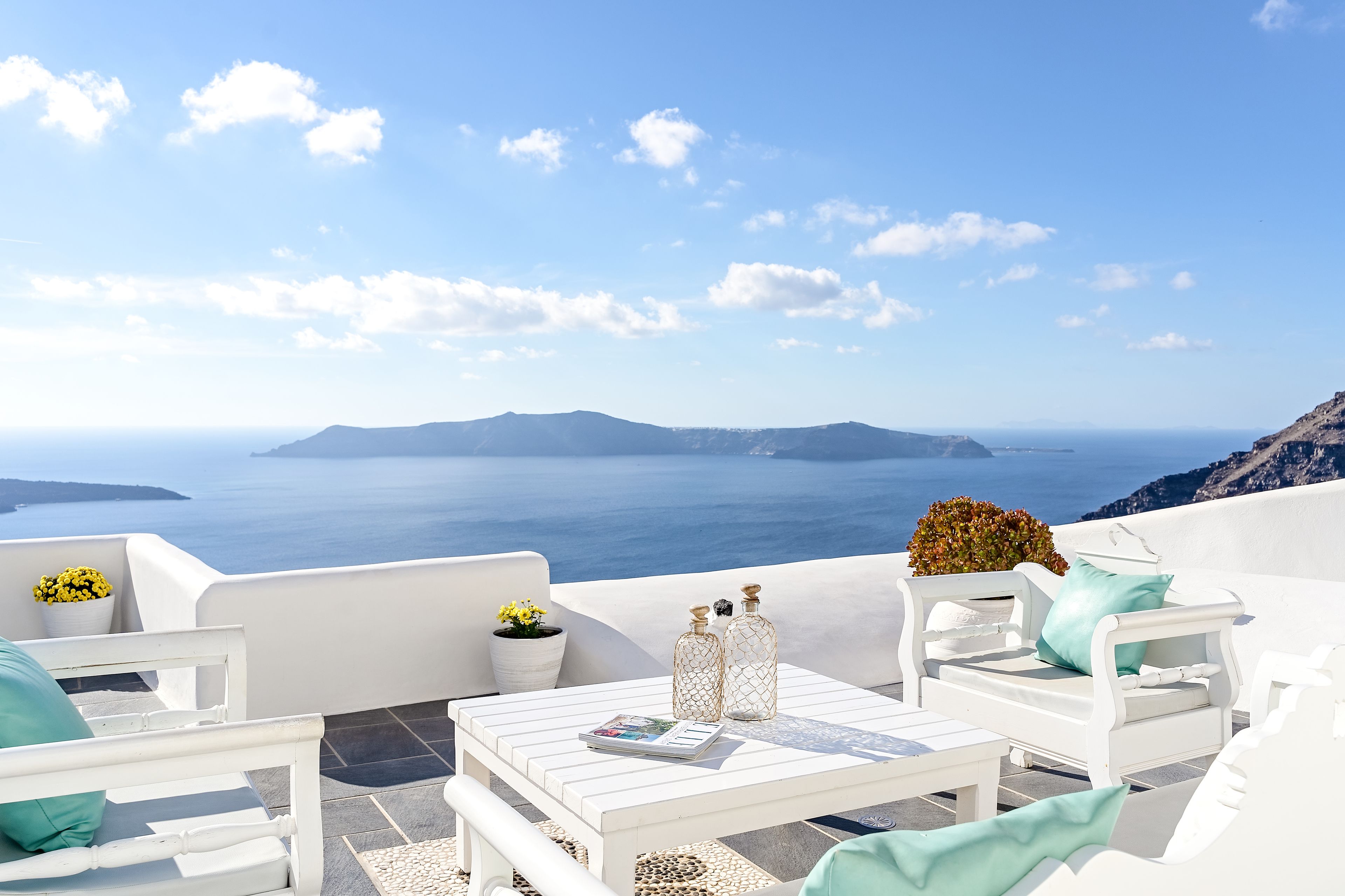 Un espace extérieur aménagé avec des meubles blancs, comprenant une table, des chaises et des plantes en pot.