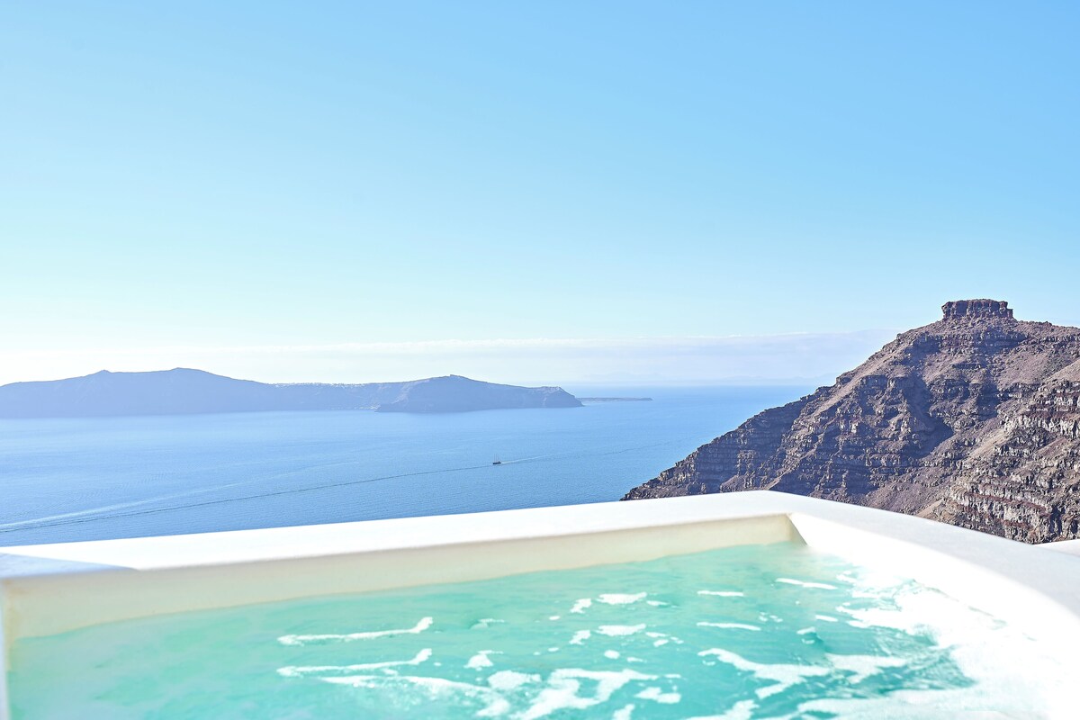 Una vista despejada de una amplia piscina infinita blanca con agua turquesa, que domina una costa escarpada y el mar.