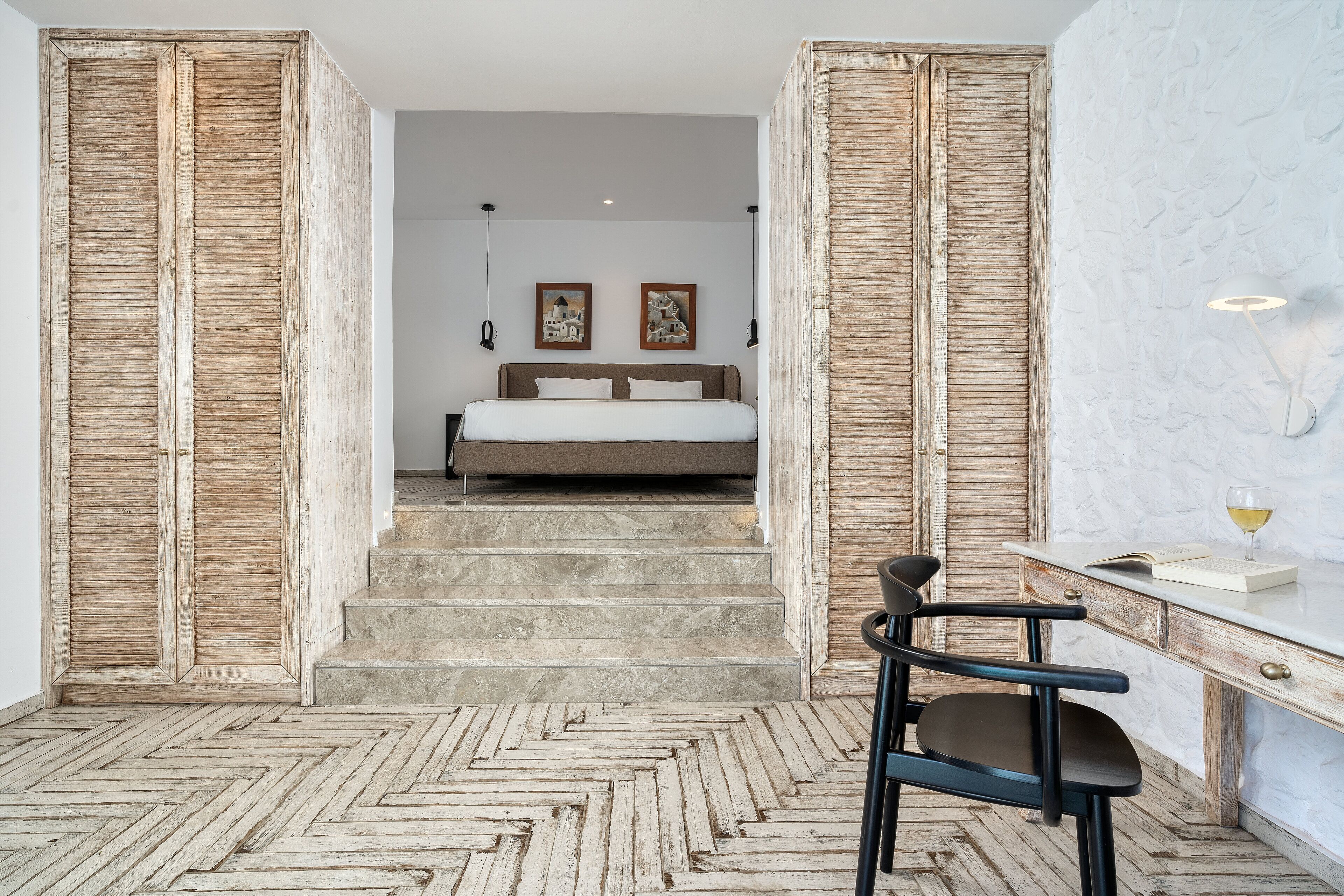 Een slaapkamer met een bed, een bureau en een stoel. Er hangen twee schilderijen aan de muur.