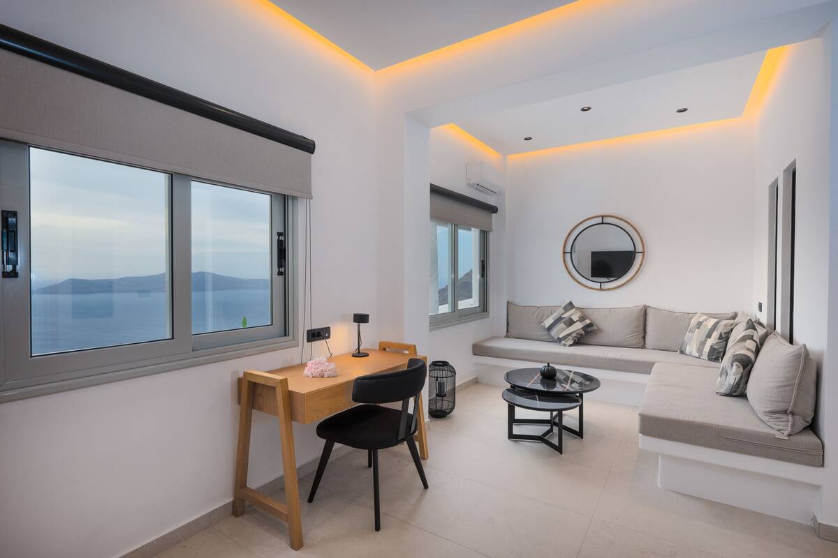 Uma sala de estar moderna com um sofá, uma mesa de jantar e vista para o mar.