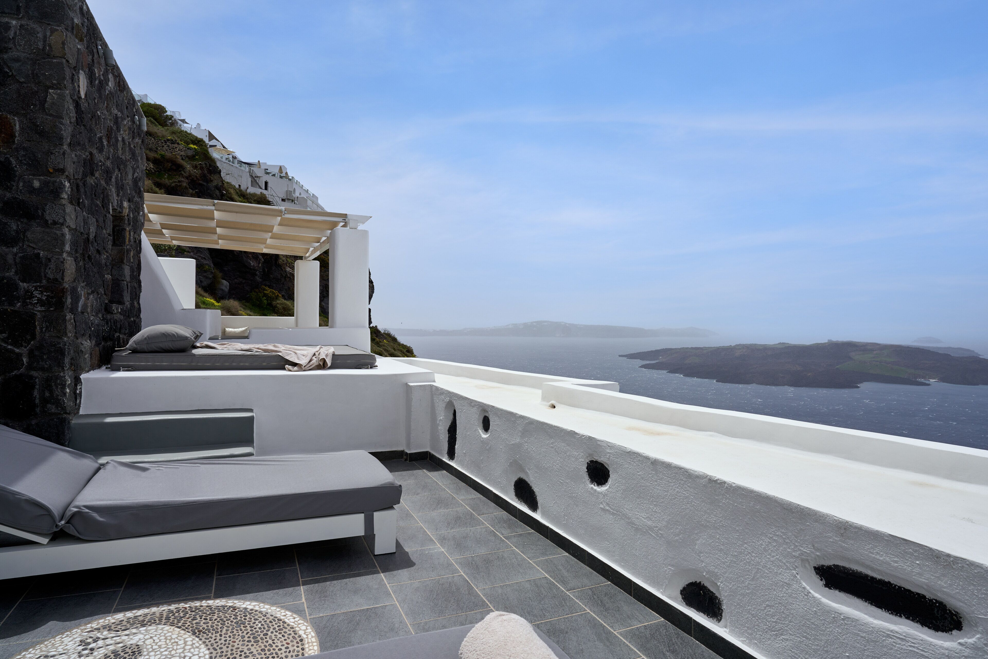 A modern outdoor seating area with a view of the sea and distant islands.