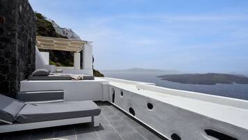 A modern outdoor seating area with a view of the sea and distant islands.