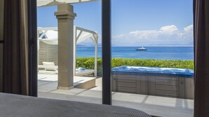 A view from a room with a large window overlooking a pool area, a hot tub, and a body of water with a boat. - Palms and Spas Corfu Villas Retreat (Corfu)