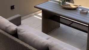 A balcony with a view of the sea and mountains, a wicker table, and a sofa. - Palms and Spas Corfu Villas Retreat (Corfu)