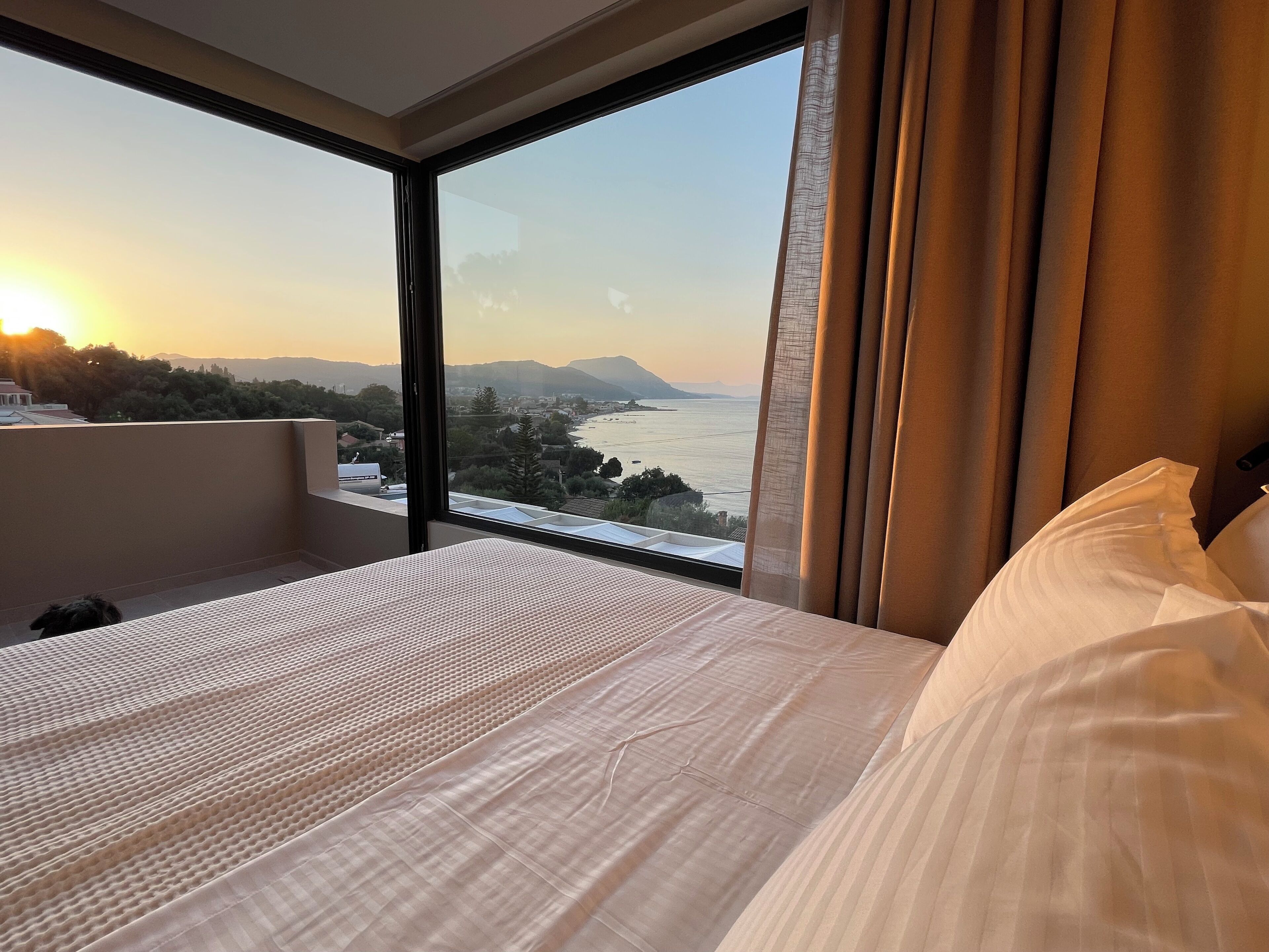 Habitación de hotel con una cama grande, vista a un cuerpo de agua y un balcón.