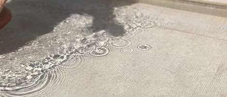 Un gros plan d’une table sur laquelle on aperçoit un verre de vin rouge, une nappe blanche et un tissu à motifs qui est drapé sur la table.