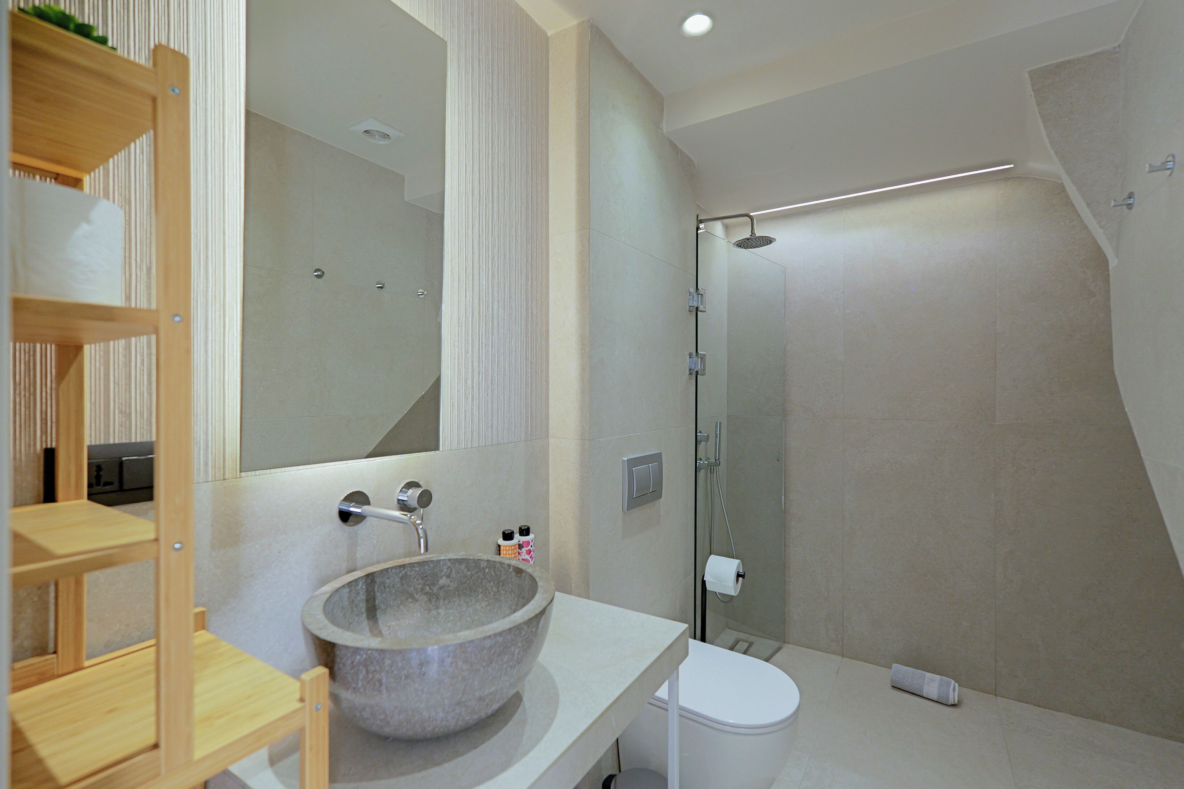 Un baño moderno con un lavabo de piedra, inodoro y ducha con mampara de vidrio.