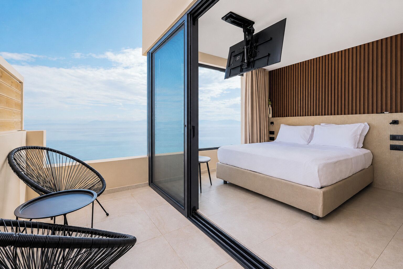 Une chambre avec un lit, une télévision, un fauteuil et une vue sur la mer.