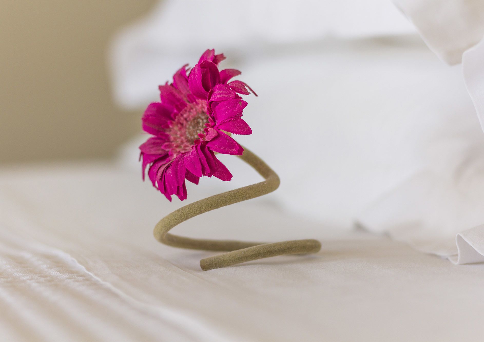 A single pink flower with a brown stem on a white surface.
