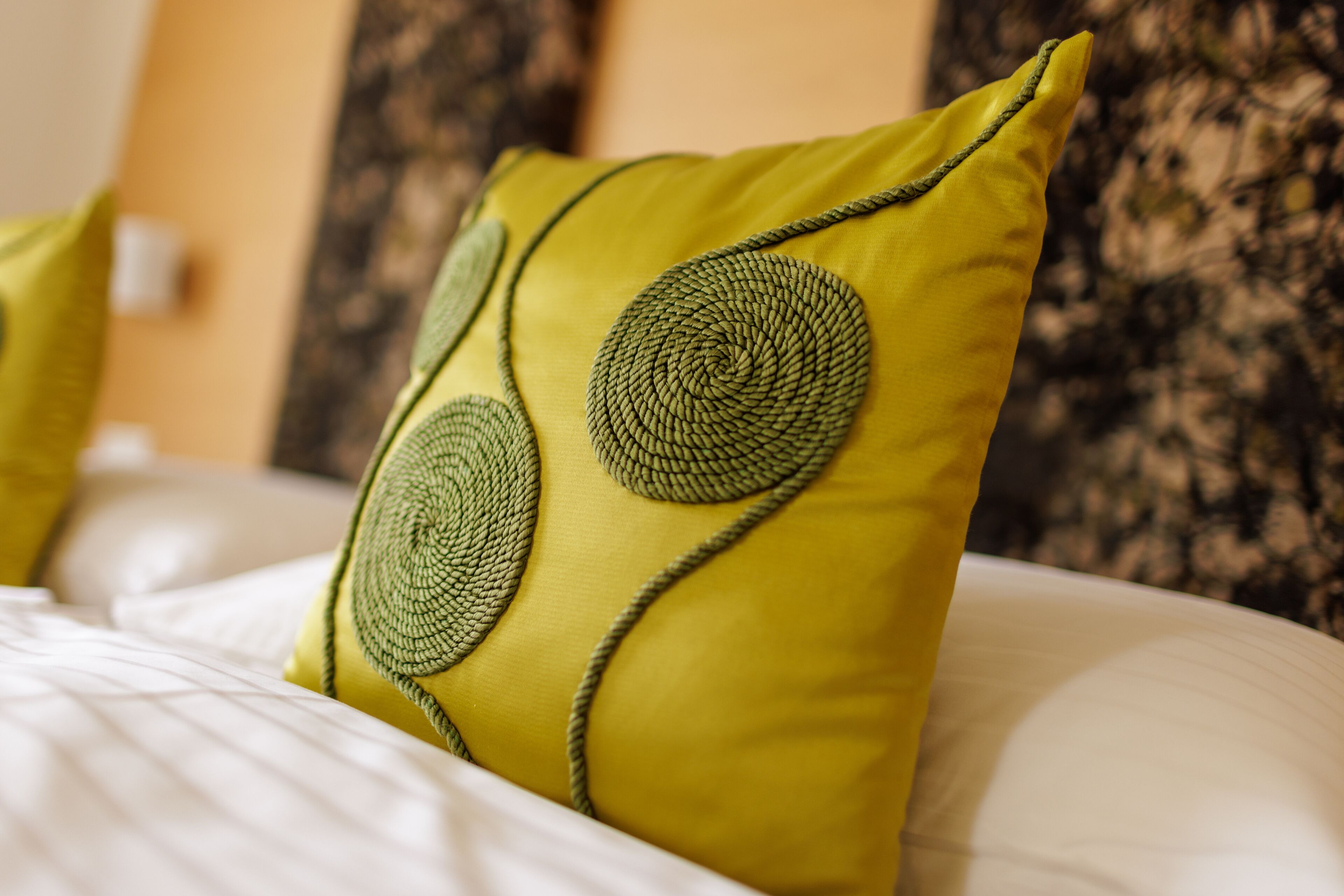 Una cama con un almohadón amarillo y un diseño circular.
