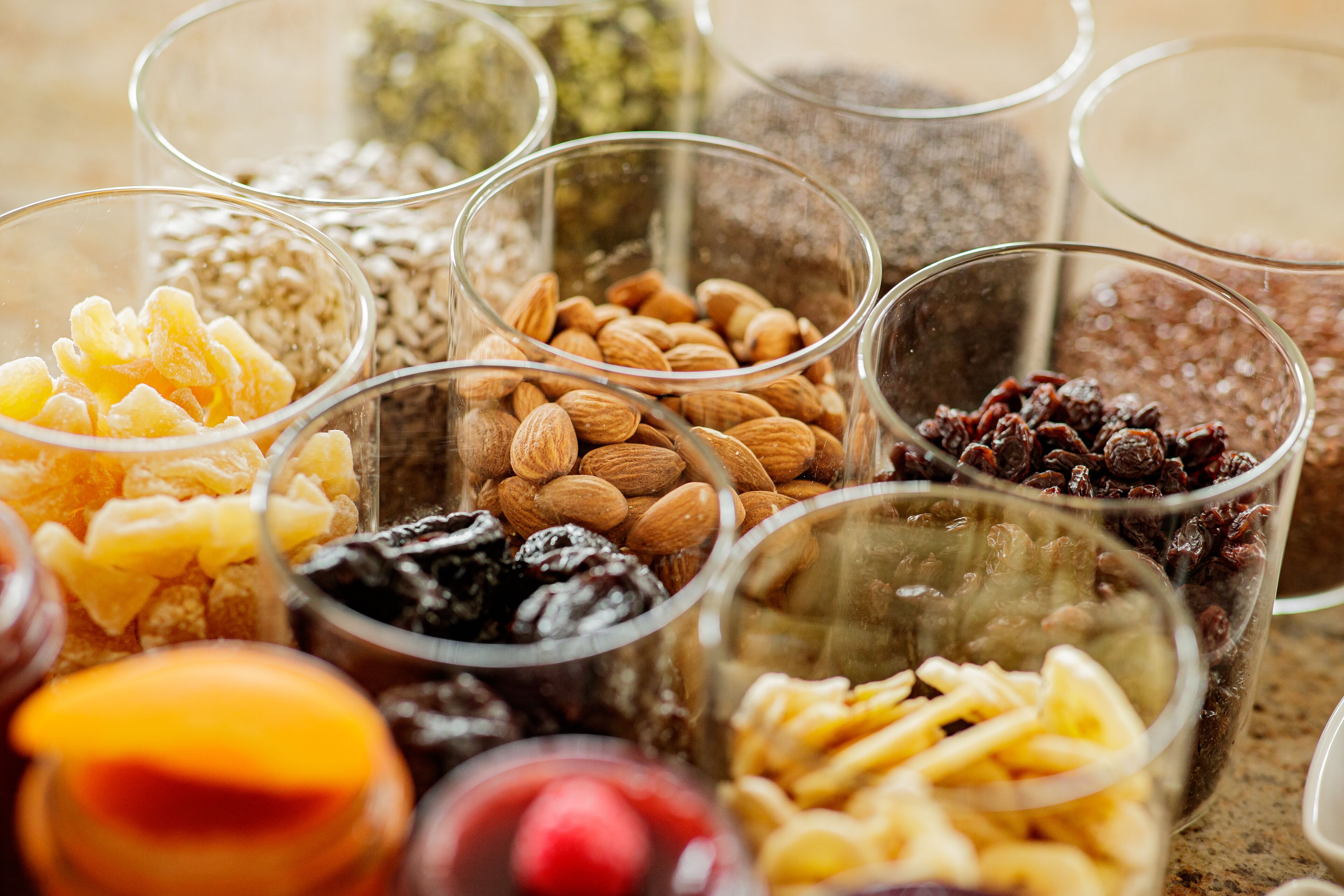 A variety of nuts and dried fruits in clear glass containers.