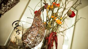 Un gallo decorativo en un florero de vidrio con flores y un lazo rojo.