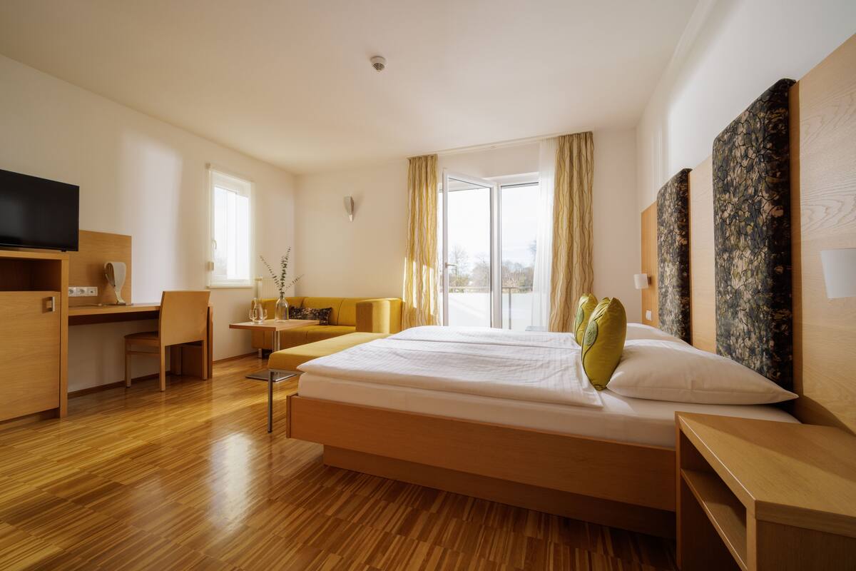 Ein modernes Hotelzimmer mit einem großen Bett, einem Schreibtisch, einem Stuhl und einem Fernseher.