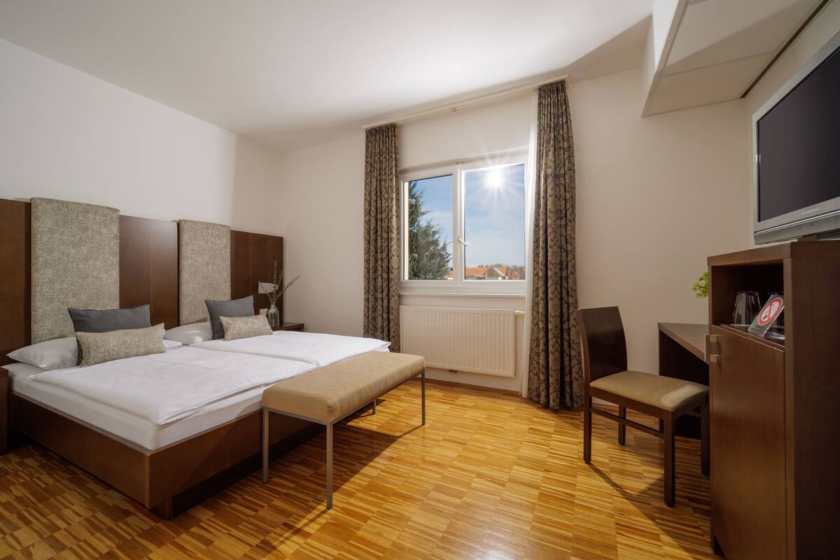 Ein Hotelzimmer mit einem großen Bett, einem Schreibtisch, einem Sessel und einem Fernseher.