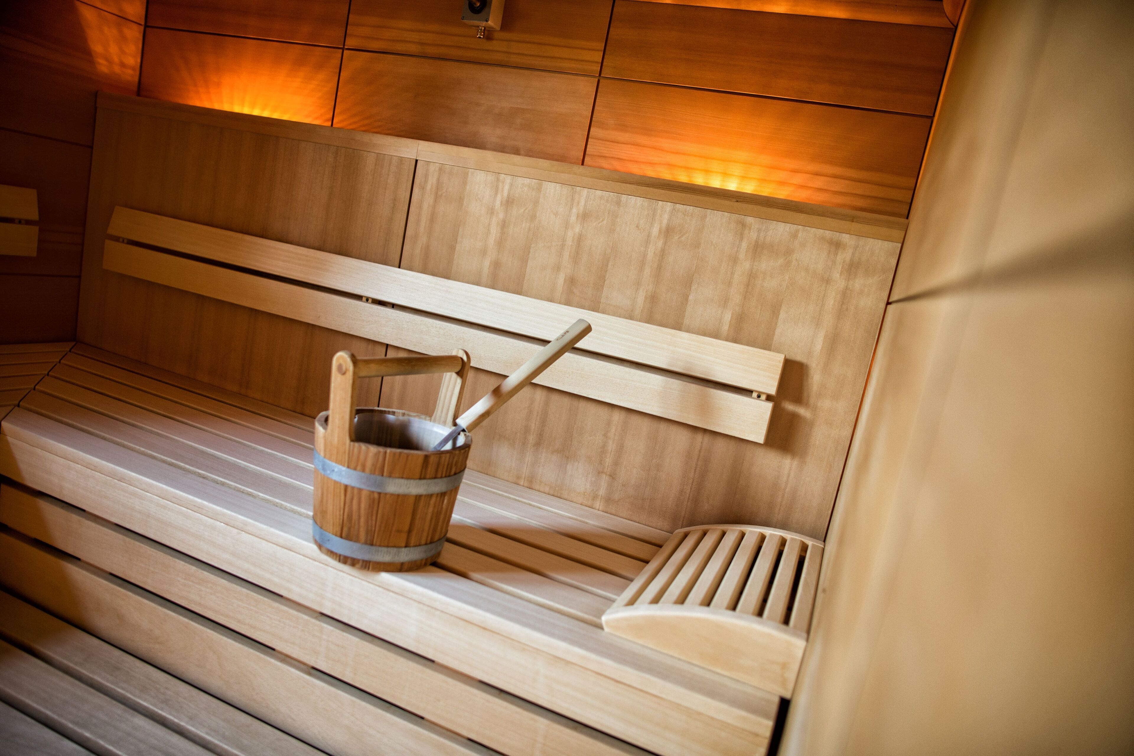 Un banco de sauna de madera con un cubo de madera y un reposapiés con listones.