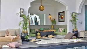Ein moderner Poolbereich im Innenbereich mit einer Couch, Topfpflanzen und einer Wandgestaltung.