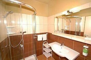 A bathroom with a shower, sink, and mirror. - Hotel Cingov (Smizany)
