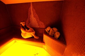 A person sitting in a bathtub with a mosaic wall behind them. - Hotel Cingov (Smizany)